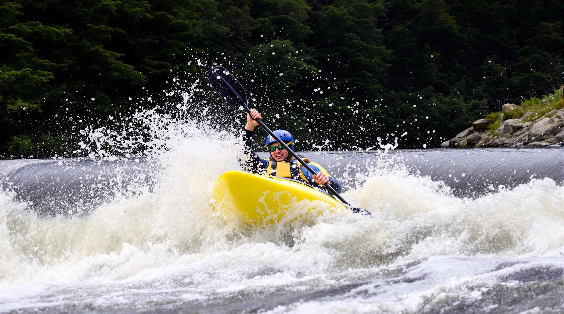 Whitewater kayaker punching through a rapid
